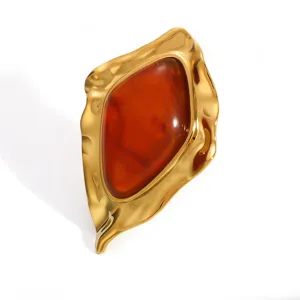 Close-up of retro irregular geometric gold-plated earring with amber resin stone