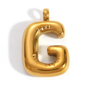 Détail macro du pendentif lettre G en acier inoxydable doré avec une finition brillante