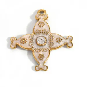 Close-up of gold-plated stainless steel cross pendant with white enamel and clear stone