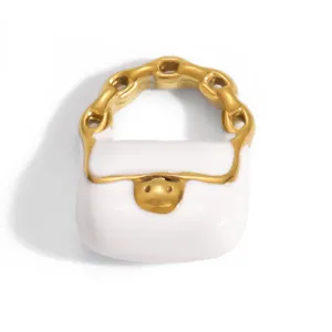 Detailed view of white enamel and gold-plated handbag-shaped stainless steel charm