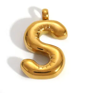 Gros plan d'un pendentif en acier inoxydable plaqué or 18k en forme de lettre S ronde