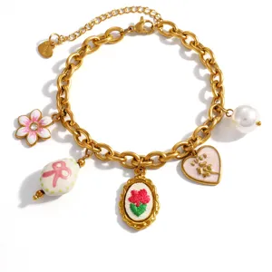 Gold-plated stainless steel charm bracelet with flower, heart, and pearl pendants close-up