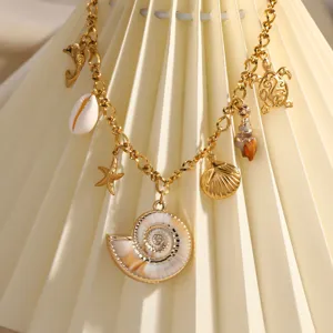 Dettaglio di collana in acciaio dorato con ciondoli marini e conchiglie naturali.