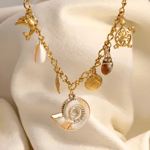 Dettaglio macro di collana marina dorata con ciondoli a forma di conchiglia, tartaruga e mollusco