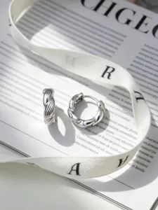 Vista dettagliata di orecchini a cerchio intrecciati in argento 925 su libro