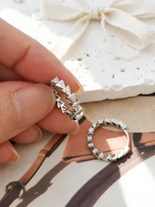 Detalle de pendientes de aro en plata S925 con diseño geométrico de circonitas y triángulos