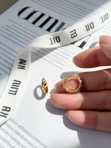 Nahaufnahme von minimalistischen S925 Silber vergoldeten Wellen-Creolen in der Hand