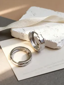 Primer plano de pendientes de aro de plata S925 con textura geométrica en piedra