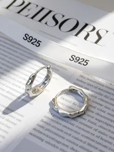 Nahaufnahme von minimalistischen, unregelmäßig gewellten S925 Sterling Silber Creolen.