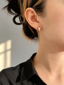 Primo piano di un orecchino a cerchio minimalista in argento sterling S925 indossato