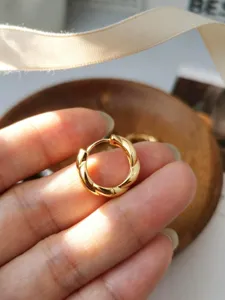 Primo piano di un orecchino a cerchio intrecciato in argento 925 placcato in oro.