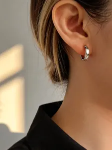 Primo piano di un orecchino a cerchio in argento S925 minimalista indossato all'orecchio