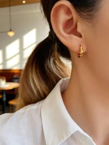 Nahaufnahme eines minimalistischen S925 Silber vergoldeten Creolen-Ohrrings am Ohr