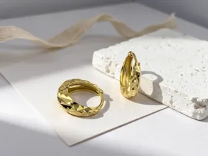 Primer plano de pendientes de aro de plata S925 dorada con textura diamantada
