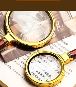 Detailed close-up of handheld reading magnifying glass with gold metal frame and wooden handle.