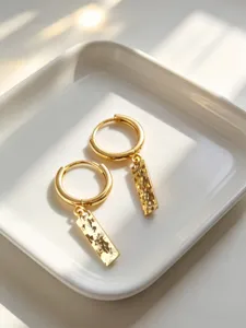 Dettaglio di orecchini a cerchio in argento S925 dorato con ciondoli rettangolari.