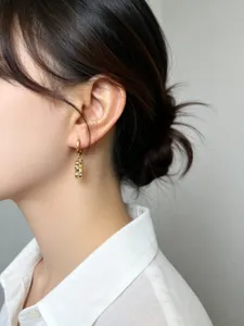 Primo piano di una modella con orecchini rettangolari in argento S925 dorato intagliato
