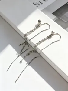 Dettaglio di orecchini minimalisti in argento S925 a nappa lunga su base bianca