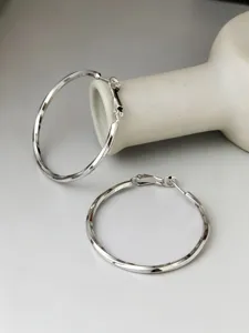 Primo piano di grandi orecchini a cerchio Mobius in argento sterling S925 con finitura lucida.
