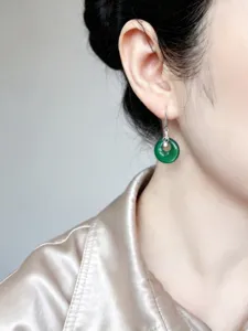 Detalle de pendiente de jade con gancho de nota musical en plata S925 en la oreja