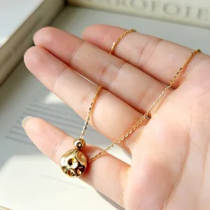Collana minimalista in argento S925 placcato oro con ciondolo a sfera testurizzata.