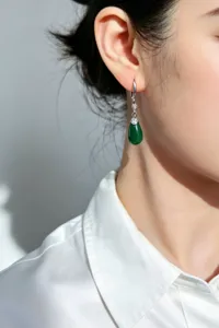 Primer plano de elegante pendiente de calcedonia verde en forma de gota en oreja