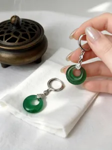 Dettaglio di orecchini a cerchio in argento S925 con ciondoli di giada verde rotonda.