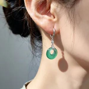 Primo piano dettagliato di orecchini a cerchio in argento S925 con giada verde.