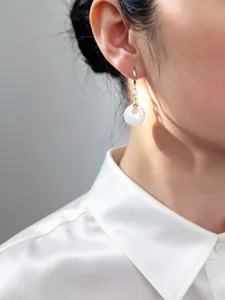Eleganti orecchini in argento S925 con ciondolo a ciambella bianco indossati da una modella.