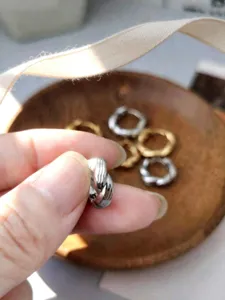 Dettaglio di orecchino a cerchio intrecciato in argento con finitura.