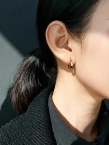 Primer plano de pendiente de aro plateado S925 con corte de estrella puesto en oreja.