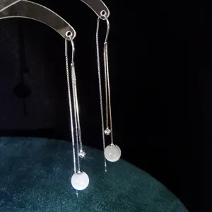 Detail van S925 zilveren lange kwastjes oorbellen met elegante witte kattenoog stenen