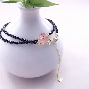 Elegante dettaglio macro di un girocollo in spinello nero con perla di quarzo fragola e oro