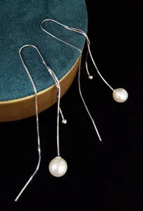 Detailweergave van elegante S925 zilveren lange kwastoorbellen met glanzende witte parels.
