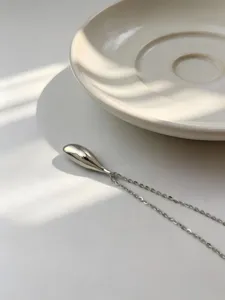 Primer plano detallado de un collar con colgante de gota en plata de ley S925 para mujer