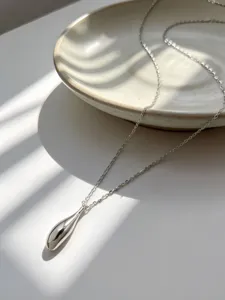 Collar con colgante de gota de agua en plata de ley S925 pulida sobre bandeja blanca