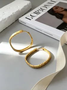 Detalle de elegantes pendientes de aro en plata S925 bañados en oro con textura.