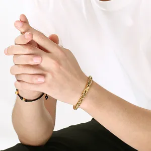 Toma detallada del elegante brazalete de cadena de metal dorado y pulsera de cuentas negras.