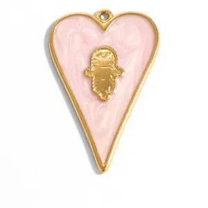 Détail du pendentif cœur en émail rose avec symbole de la main de Hamsa dorée sur blanc.
