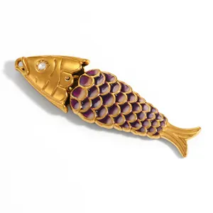 Detailed macro view of an articulated gold-plated fish pendant with purple enamel scales
