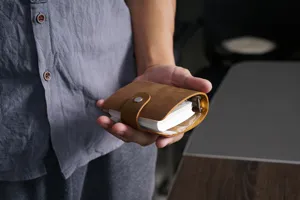 Primer plano detalle del mini cuaderno A9 de cuero con textura retro y botón presión.