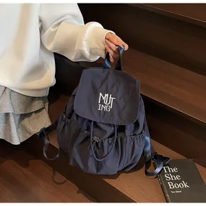Detailansicht eines dunkelblauen Nylon-Rucksacks mit weißer MUTING-Stickerei.