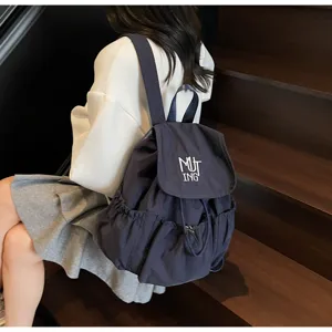 Nahaufnahme eines dunkelblauen Nylon-Rucksacks mit Kordelzug und MUT-ING-Stickerei.