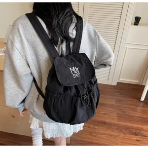 Ein schwarzer Nylon-Rucksack mit Kordelzug an einem Schülermodell in einem Raum.