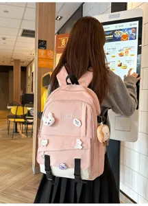Détail d'un sac à dos bicolore rose et blanc avec des épinglettes et porte-clés