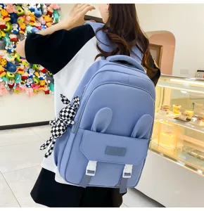 Jeune fille portant un sac à dos bleu étanche avec oreilles de lapin et pendentif.