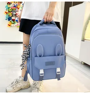 Gros plan d'un sac à dos scolaire bleu clair avec oreilles de lapin et charme en peluche