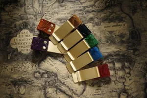 Close-up view of vintage leather brass money clips and pen holders arranged on a map background.