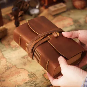 Close-up detail shot of the handmade retro genuine leather notebook with rustic wrap-around strap.