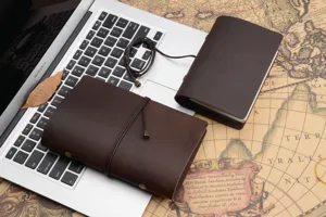 Detail shot of vintage handmade leather journal set, retro brown traveler notebook on map.